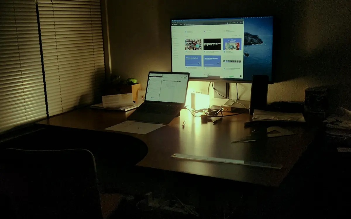 Desk at night with a laptop and a desktop monitor running an app