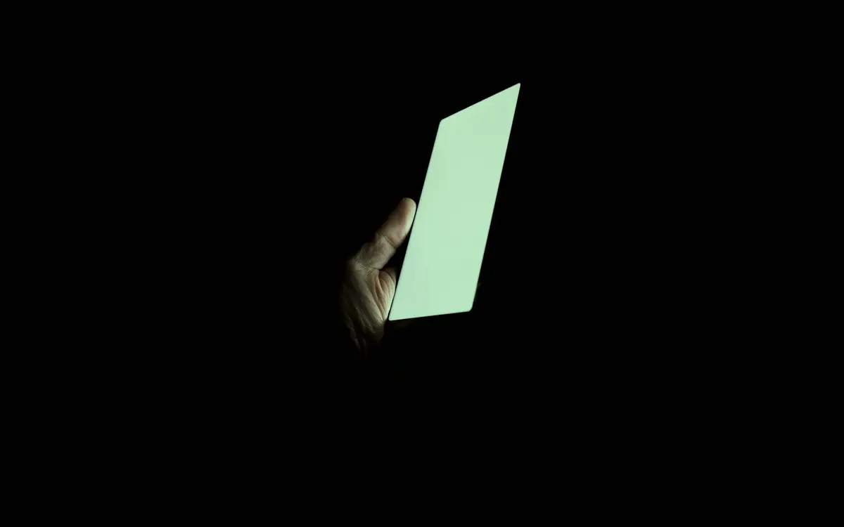 Hand holding a glowing smartphone in the dark